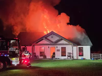 image shows white hose with black roof on fire