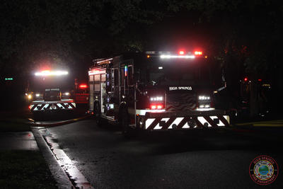 image of two fire trucks with lights on at scene of a house fire 
